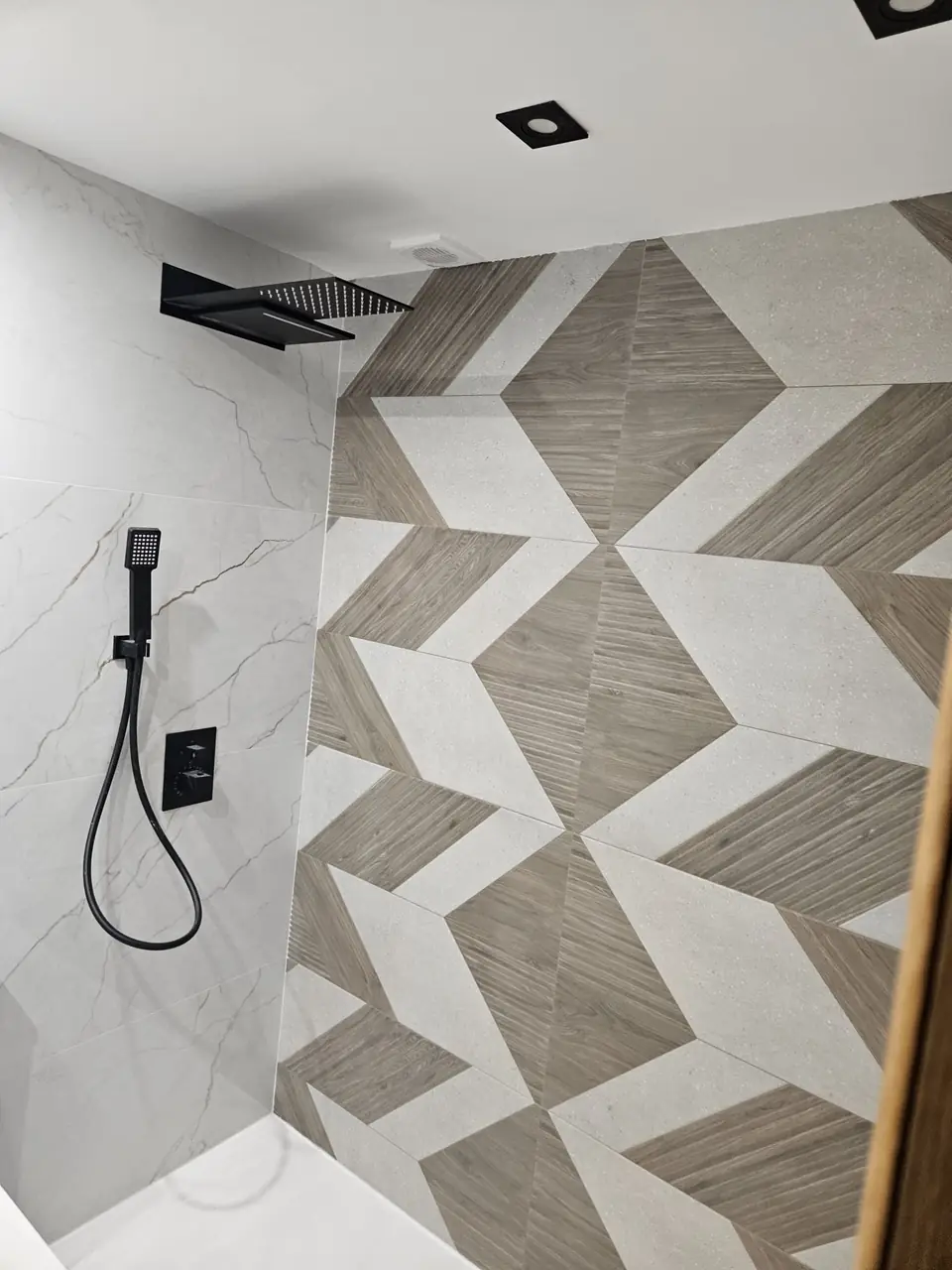 Ducha con porcelánico geométrico efecto madera y mármol, rociador cascada y grifería negra empotrada
