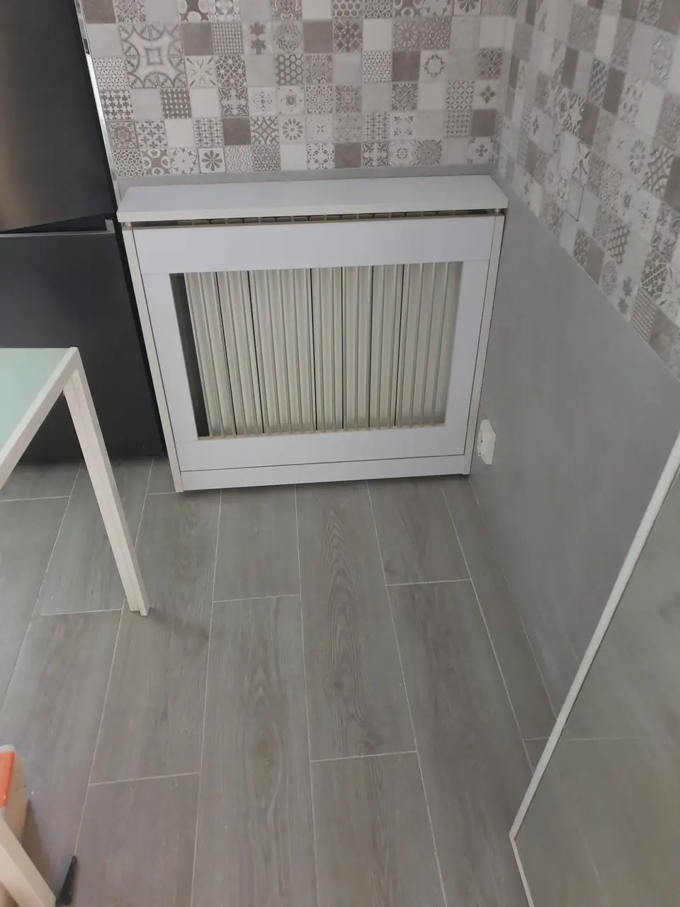 Cocina con suelo porcelánico imitación madera gris, zócalo liso, azulejo hidráulico y cubrerradiador a medida